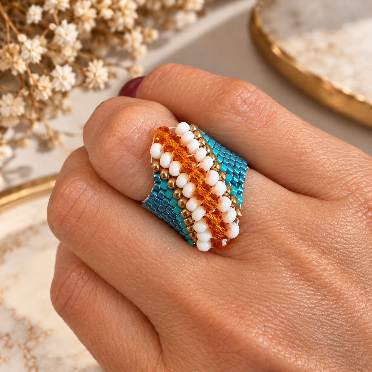 Cascade Miyuki beaded ring worn on hand with turquoise, white, gold-tone and faceted amber-orange bead details