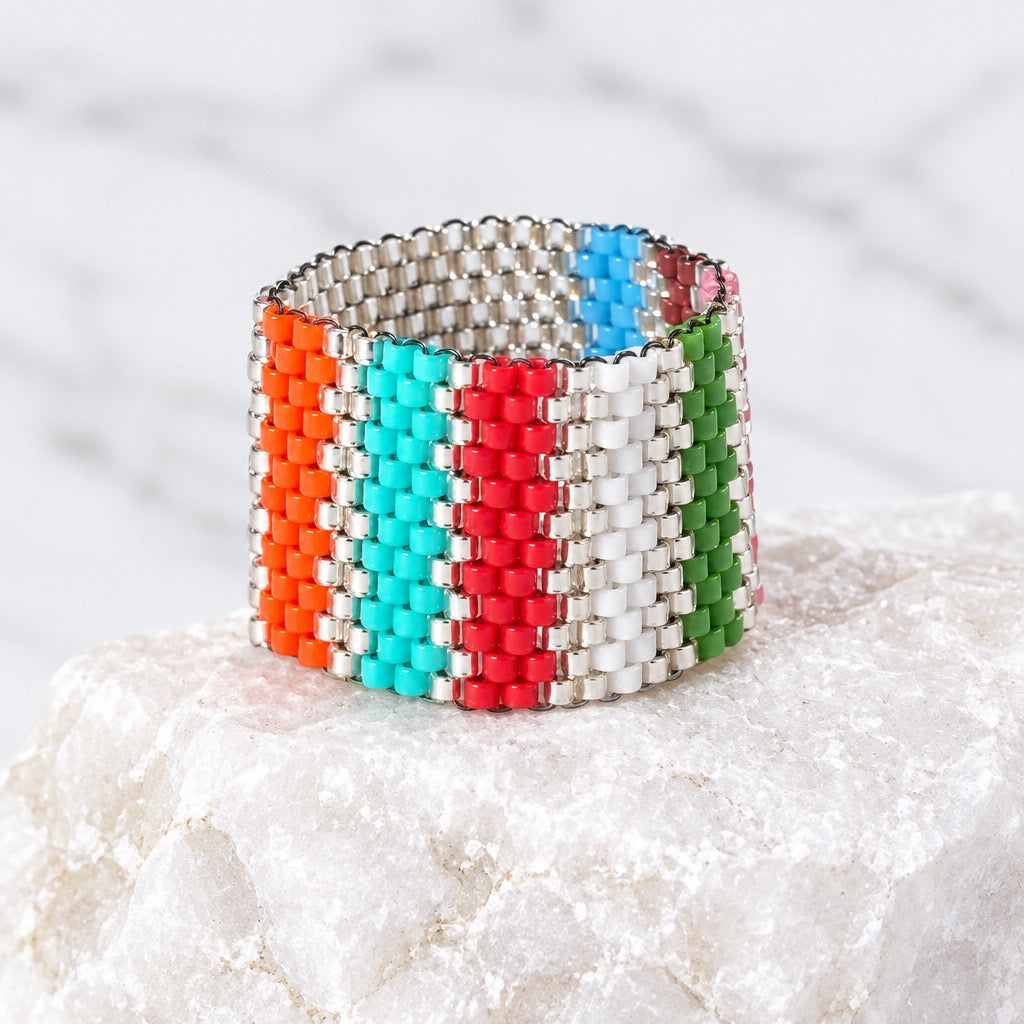 Chromatic multicolor Miyuki Delica ring displayed on a natural stone surface