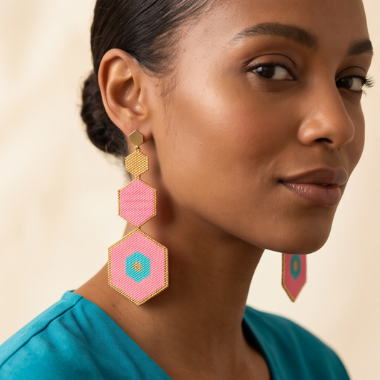 Model wearing Dailot pink and turquoise hexagon beaded drop earrings with gold-tone borders and a teal top.