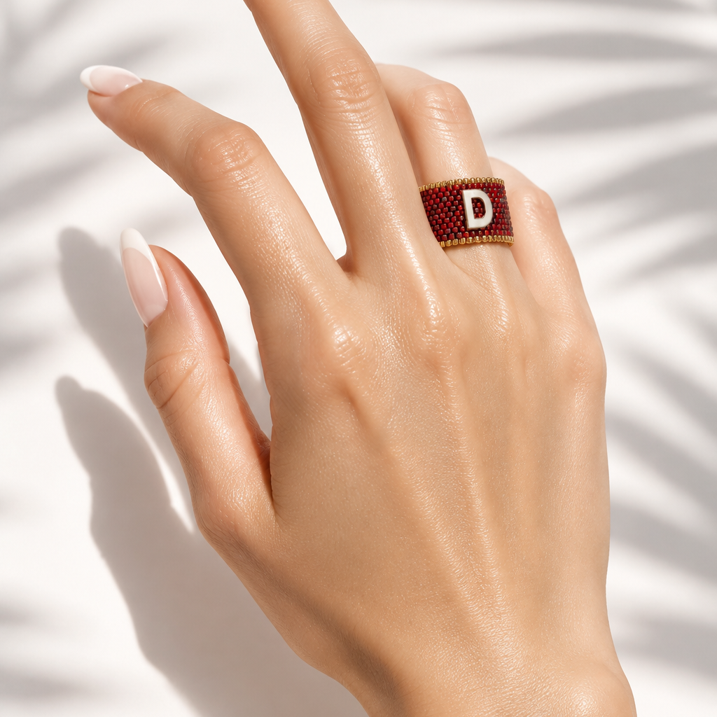 Signatus Mother of Pearl Miyuki Ring worn on hand showing its red beaded band and initial centerpiece