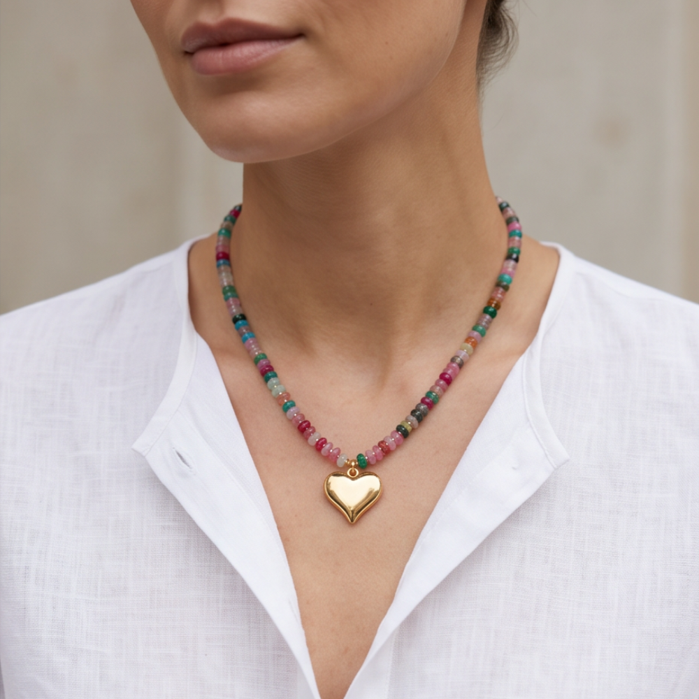 A woman with a white top wearing on a necklace made with agathe rondelle and a gold plated heart charm.