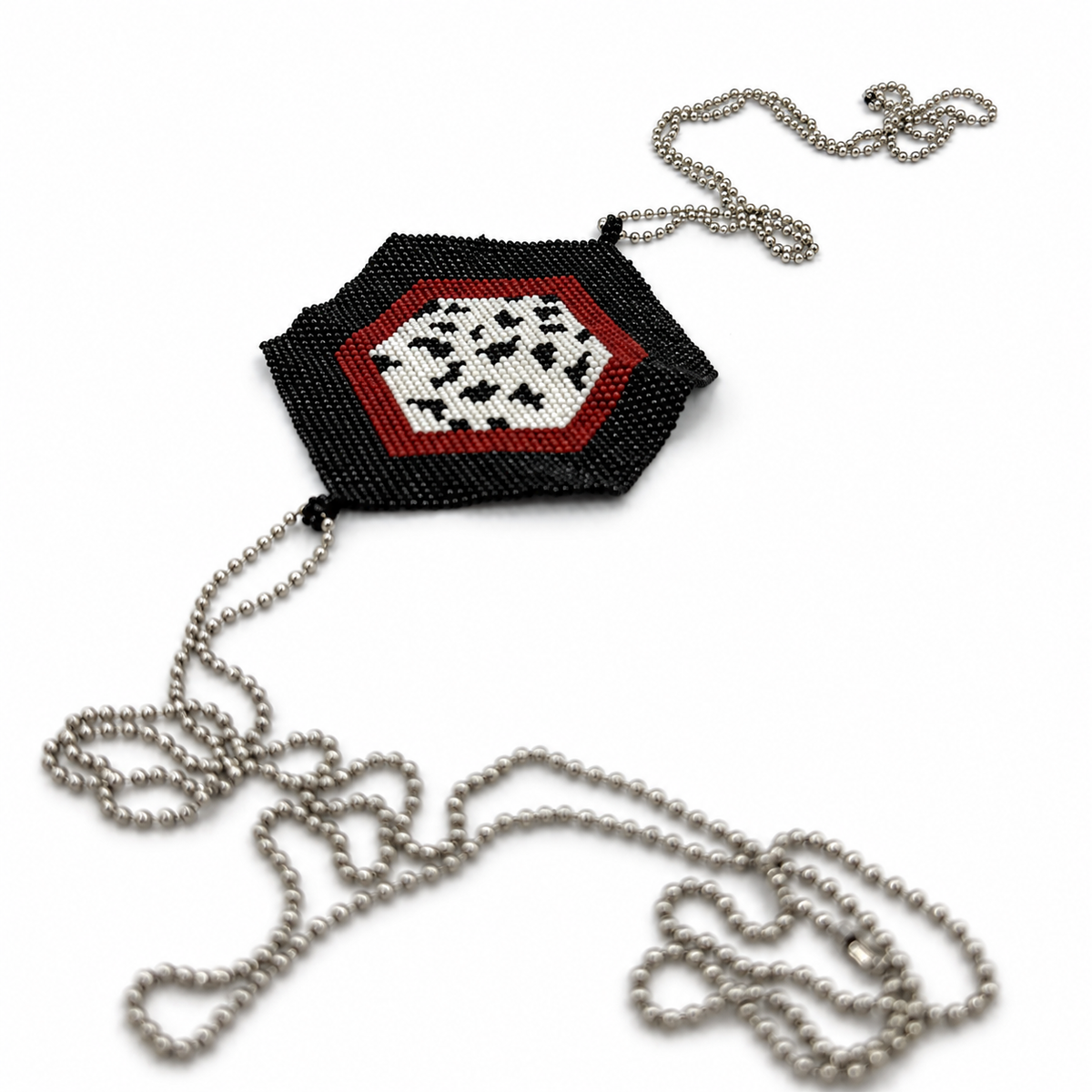 Angled view of a hexagonal beaded cross body chain with a black border, red band, white spotted center, and silver-tone chains.