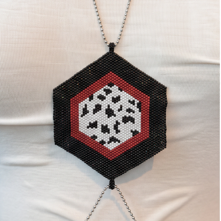 Close-up of a hexagonal Miyuki Delica centerpiece with a black border, red inner band, and black-and-white patterned center.