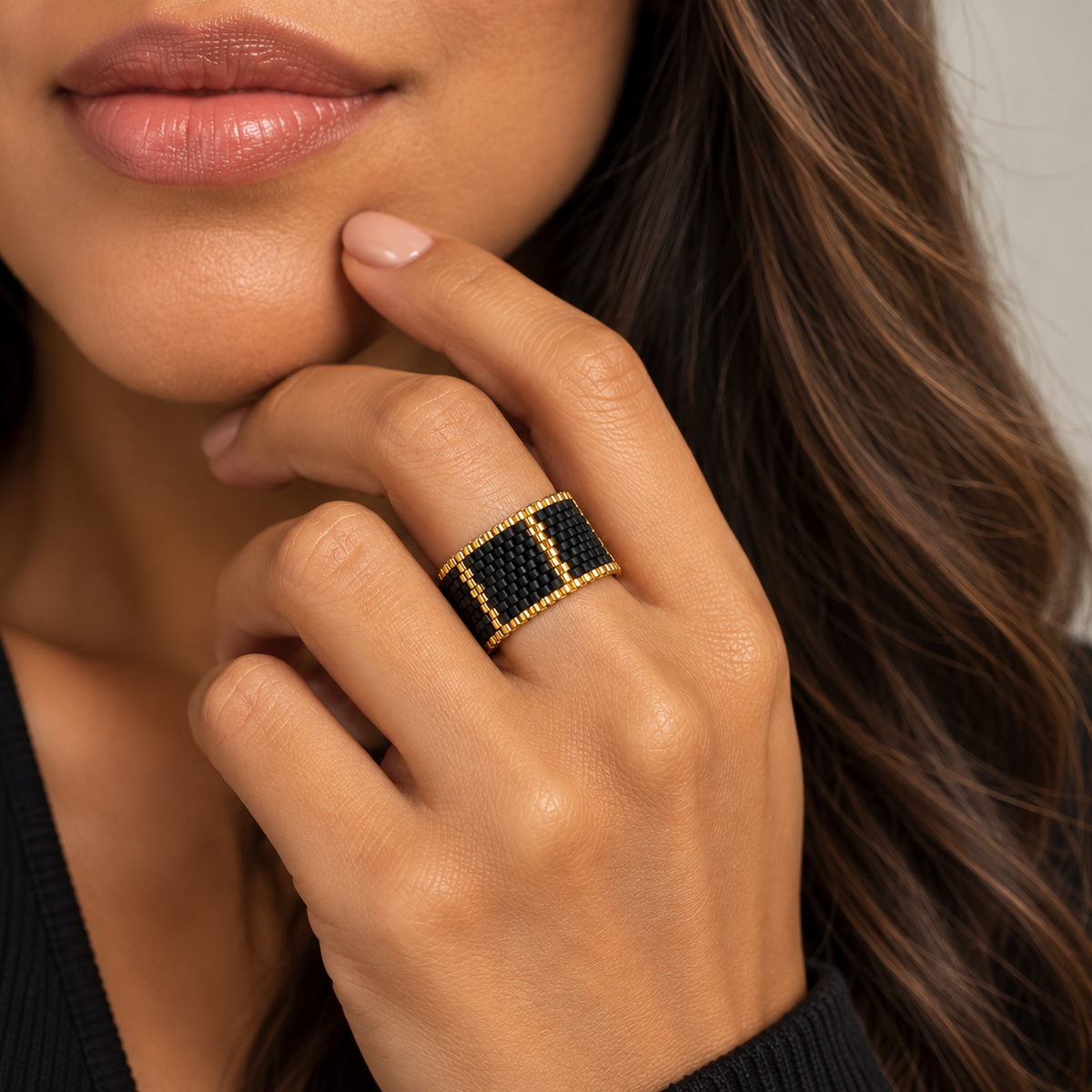 Linear black and gold-tone Miyuki Delica ring worn on a model showing its wide geometric design
