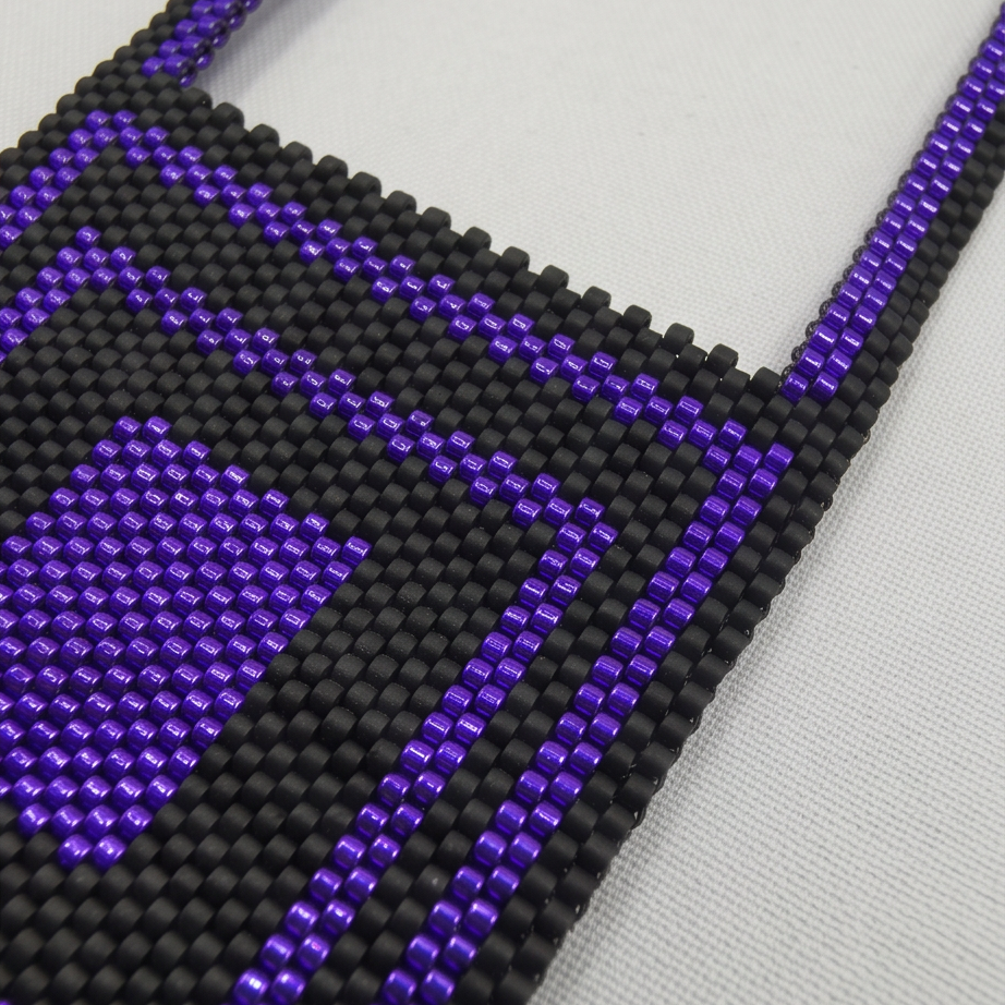 Close-up of glossy purple and matte black Miyuki Delica beads forming a square pattern on a cross body chain.