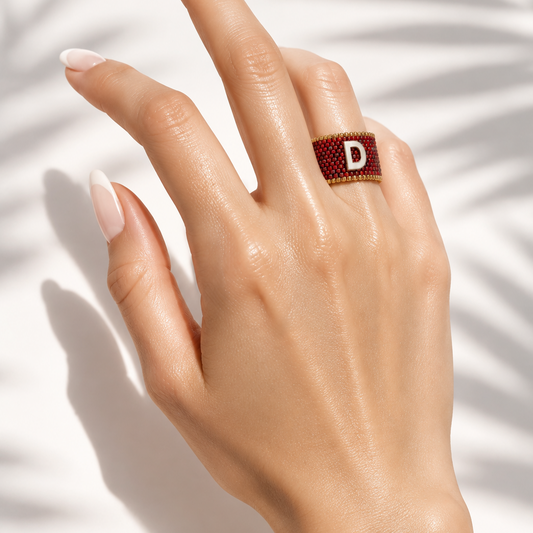 Signatus Mother of Pearl Miyuki Ring worn on hand showing its red beaded band and initial centerpiece